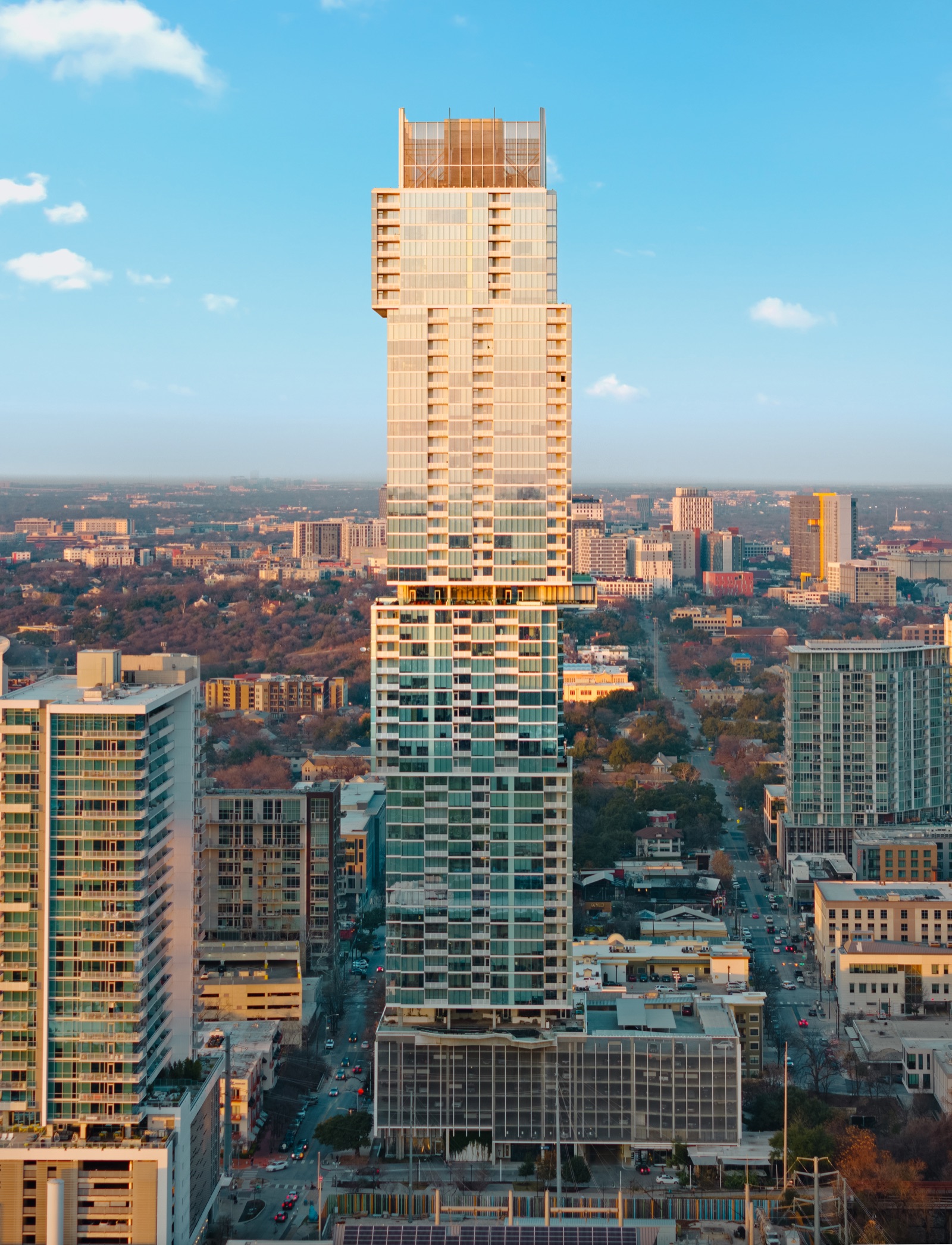 Aerial view of a downtown Austin tower and surrounding city skyline in warm evening light