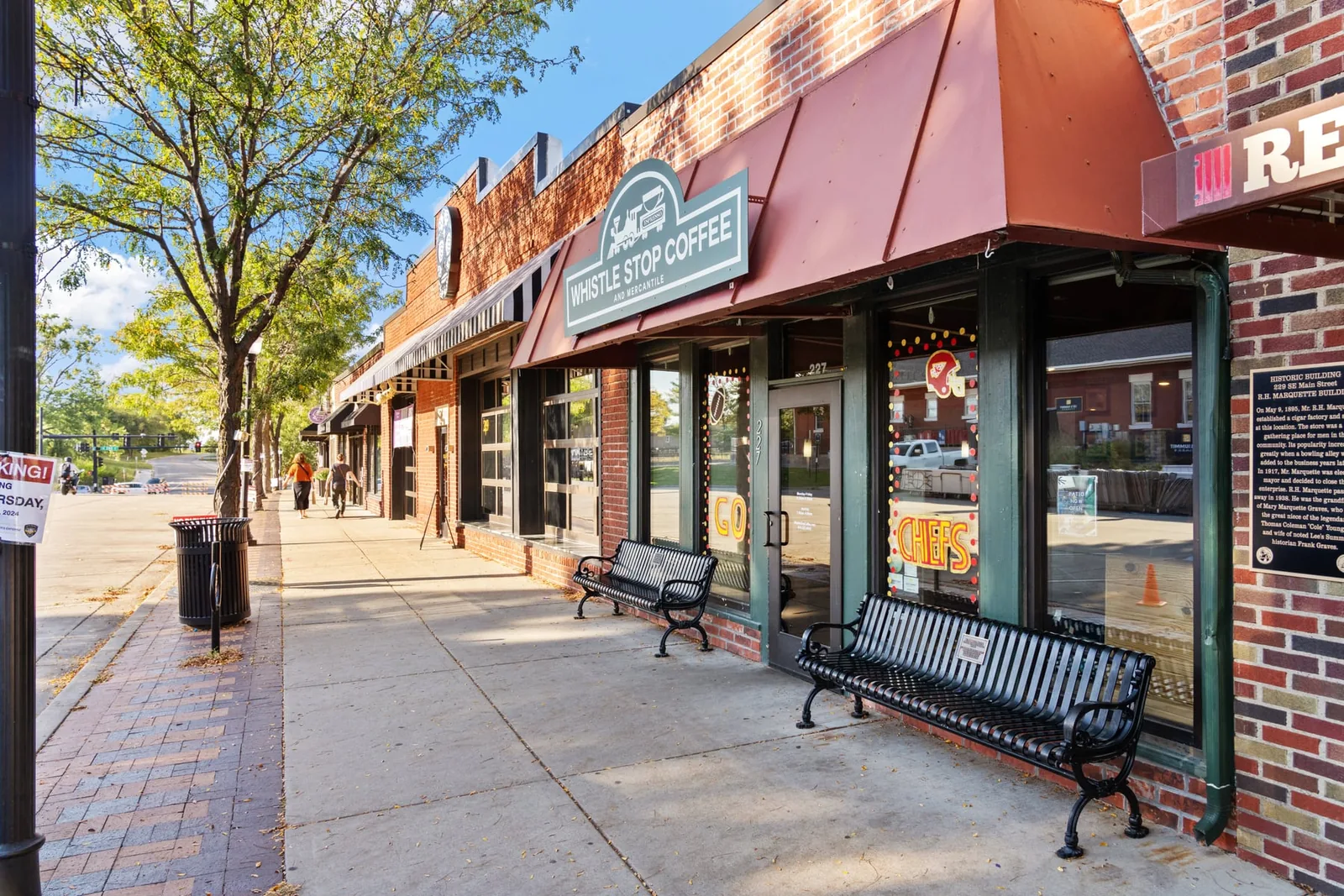 Brick storefronts and a shaded downtown sidewalk