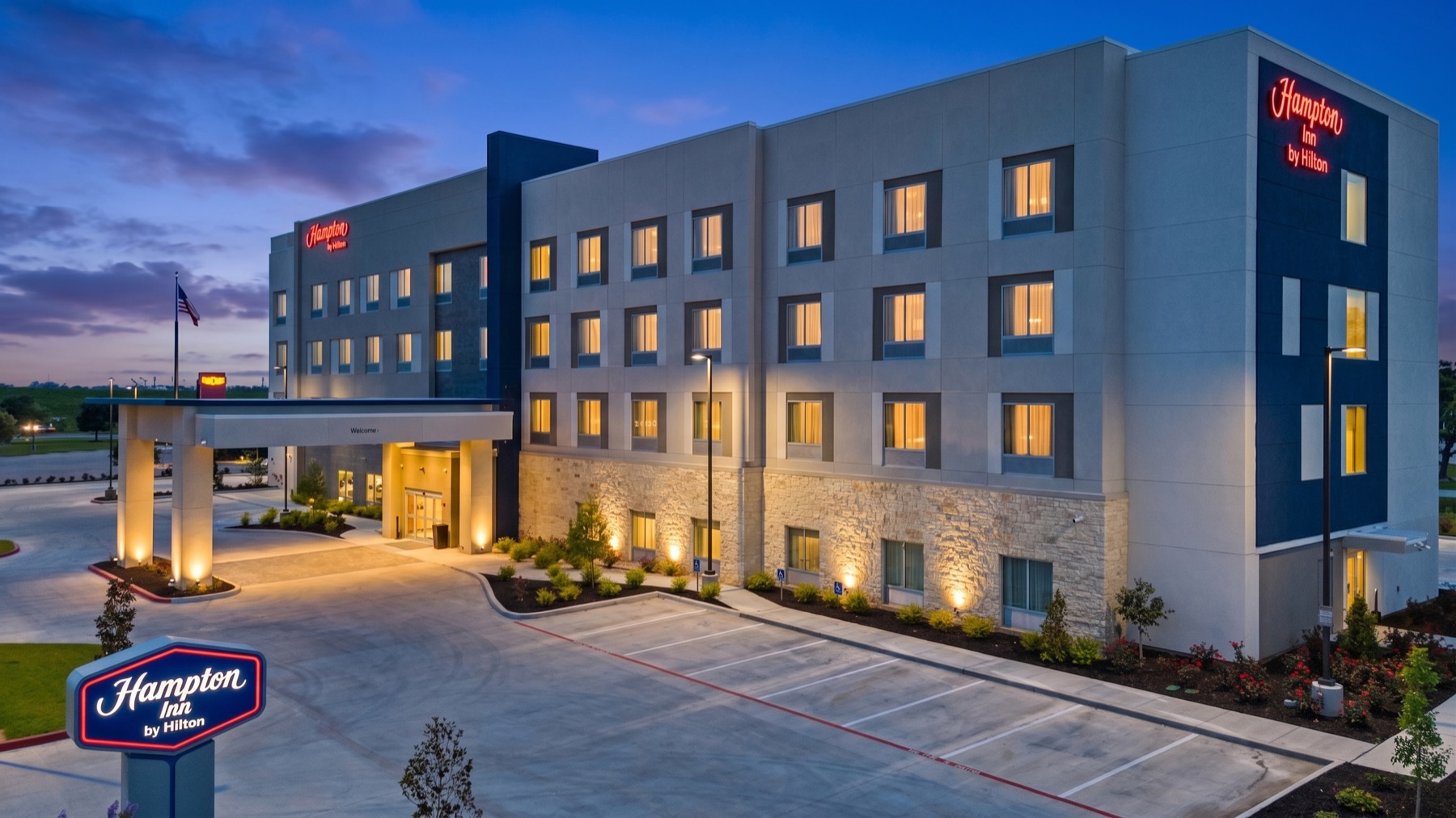 Professionally photographed Texas hotel exterior at dusk with warm lights in the guest rooms.