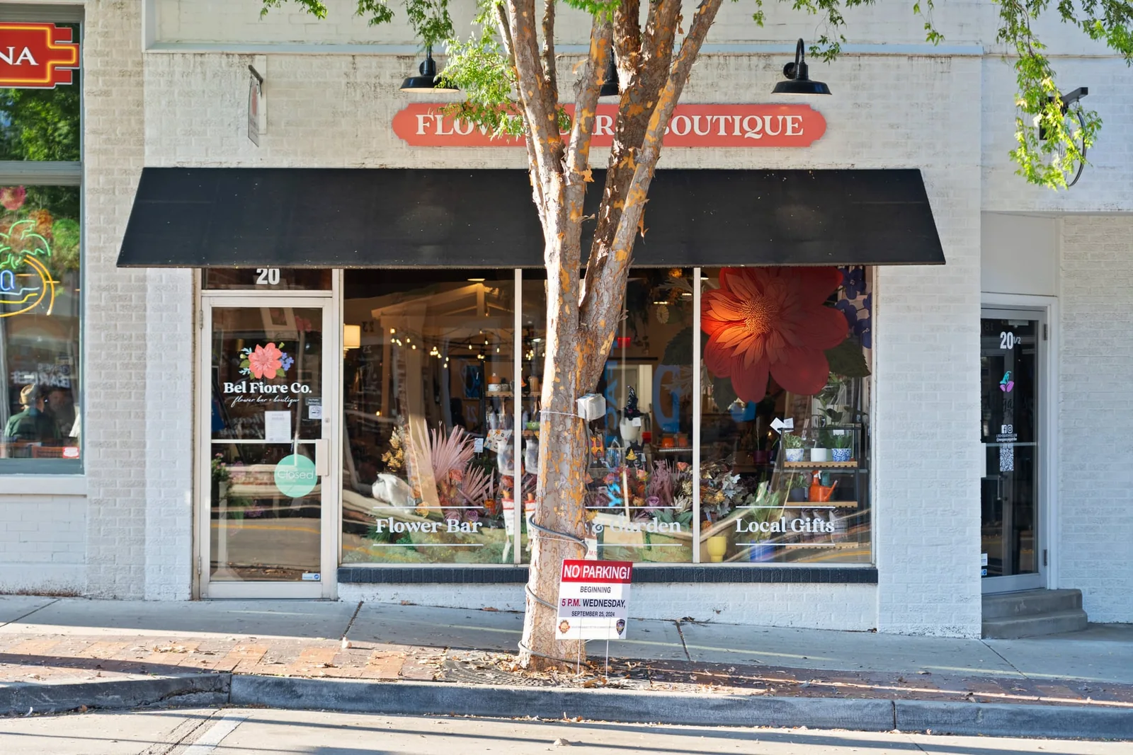Downtown boutique with a black awning and flower displays