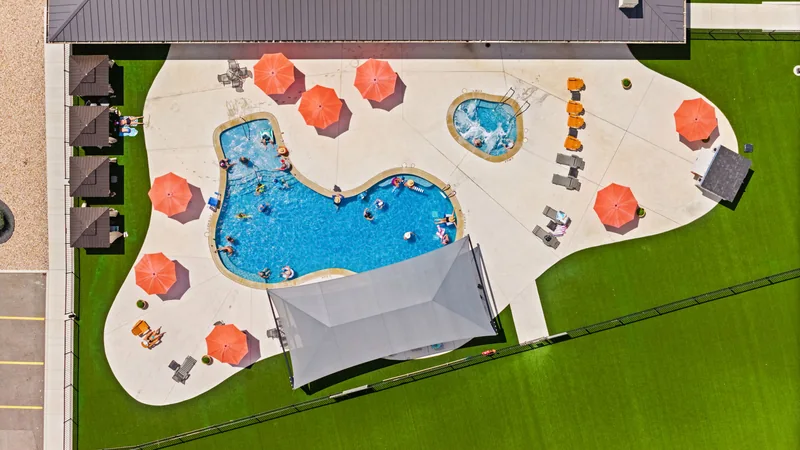 Direct overhead view of a resort swimming pool with orange umbrellas