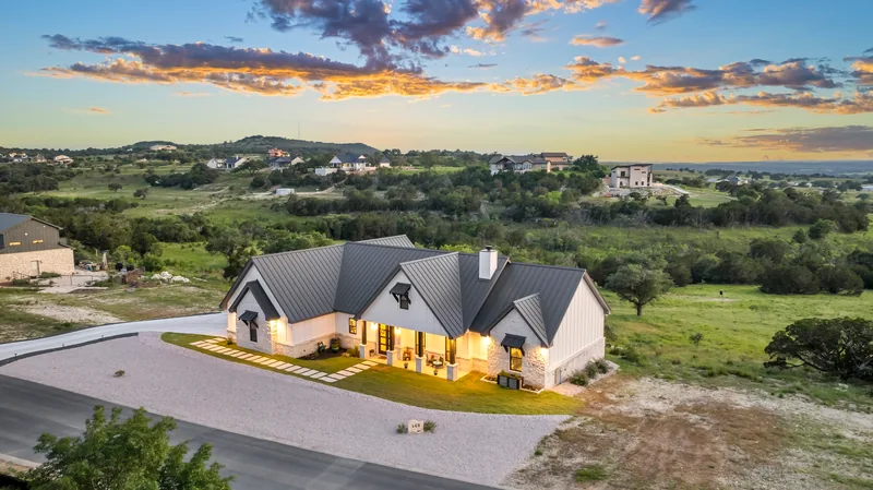 Aerial view of a home and driveway beneath a colorful evening sky