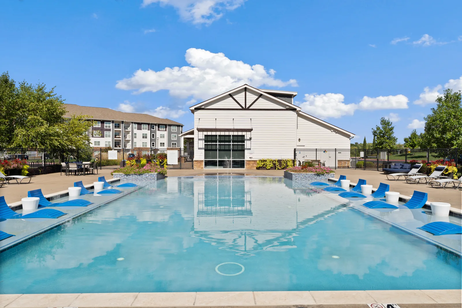 Multifamily community pool and amenity building photographed in daylight