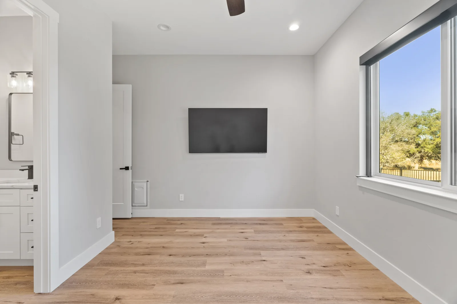 Empty bedroom with wood flooring and a wide window