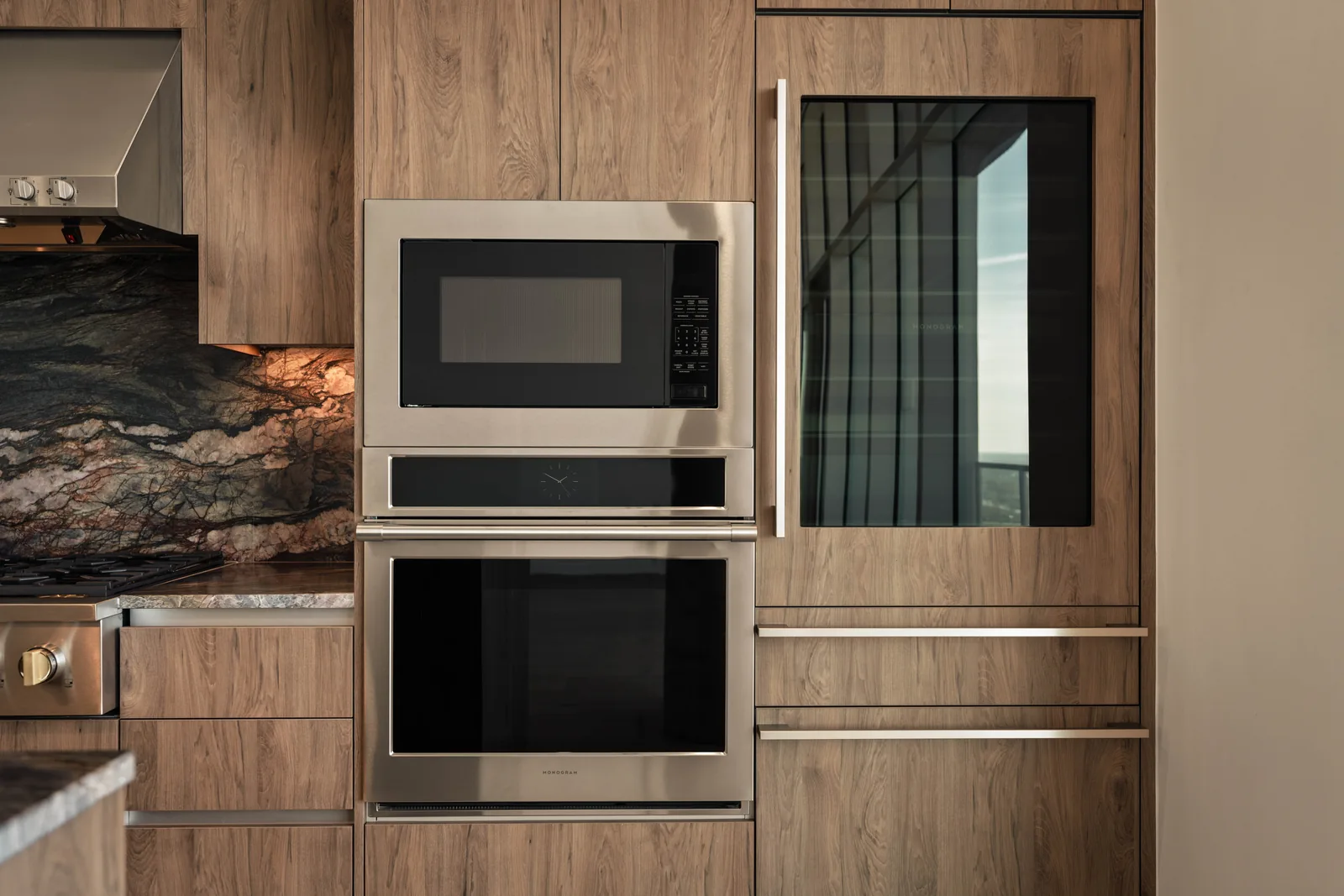 Built-in oven and wood cabinetry beside a stone backsplash