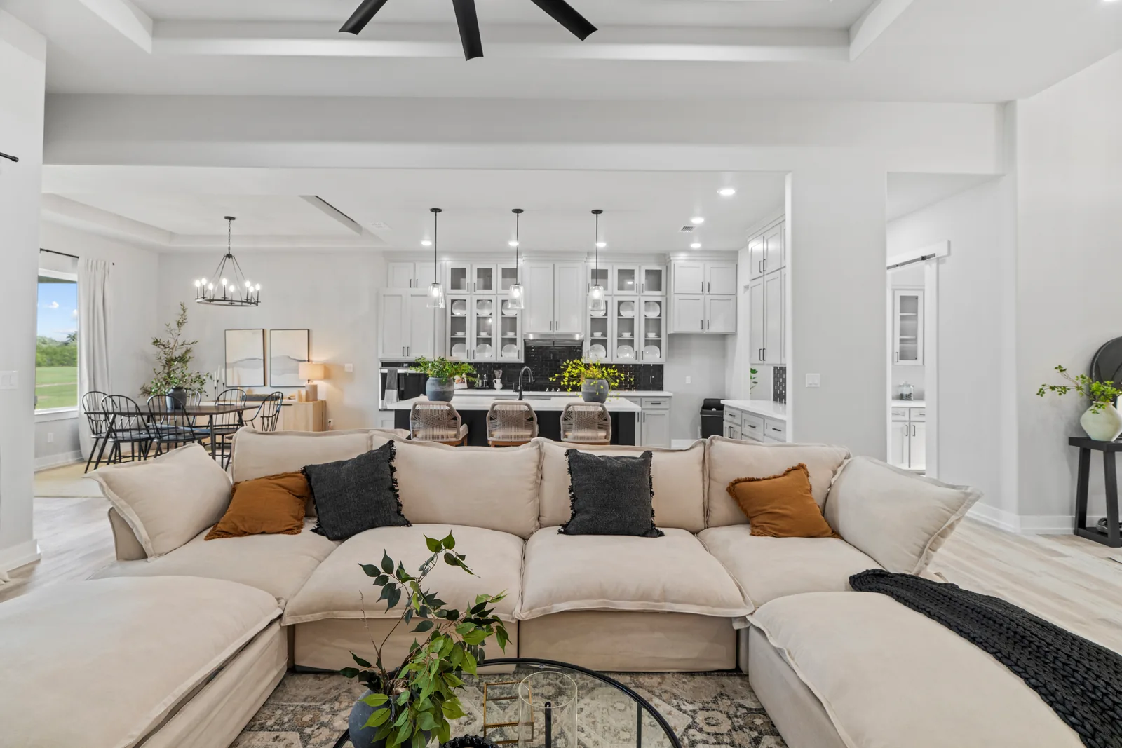 Living area and kitchen with a neutral sofa and pendant lights