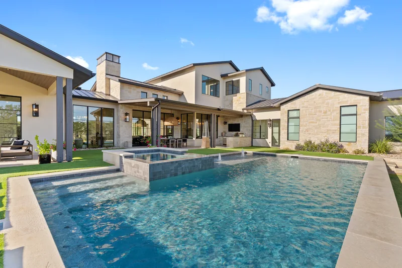 Swimming pool beside a stone home and covered terrace