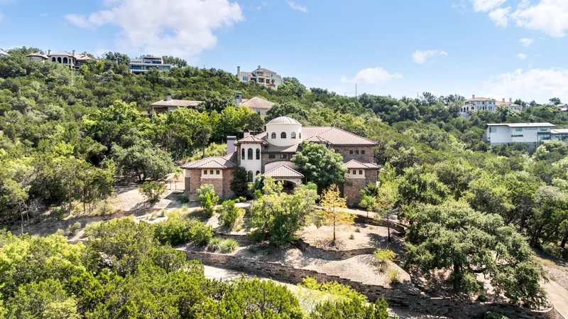 Elevated view of a large stone home nestled in wooded hills