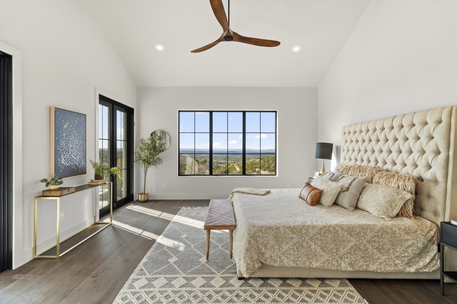 Bright bedroom with a neatly made bed and Hill Country view