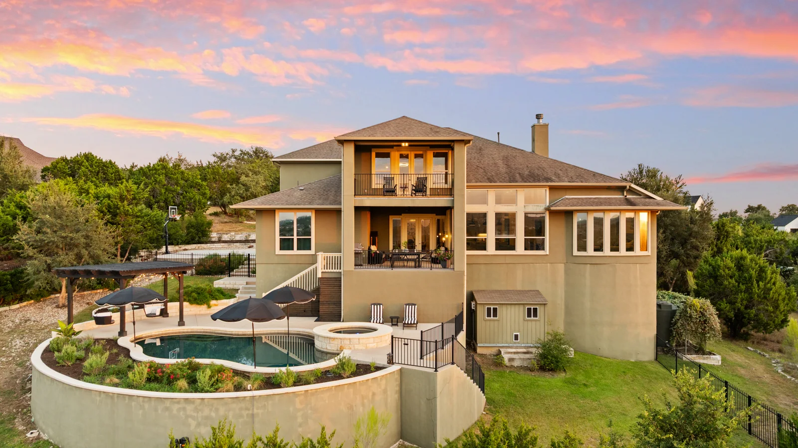 Aerial view of a hillside home and pool at sunset