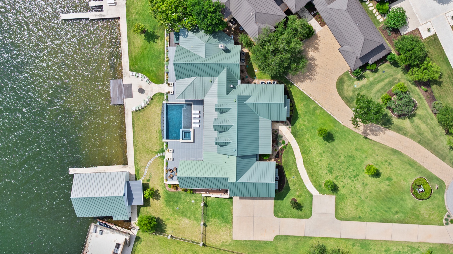 Aerial view of the lakeside property with the pool, driveway and roof layout