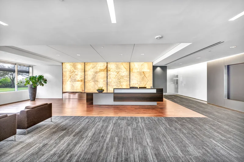 Modern office reception with a backlit stone wall and glass frontage
