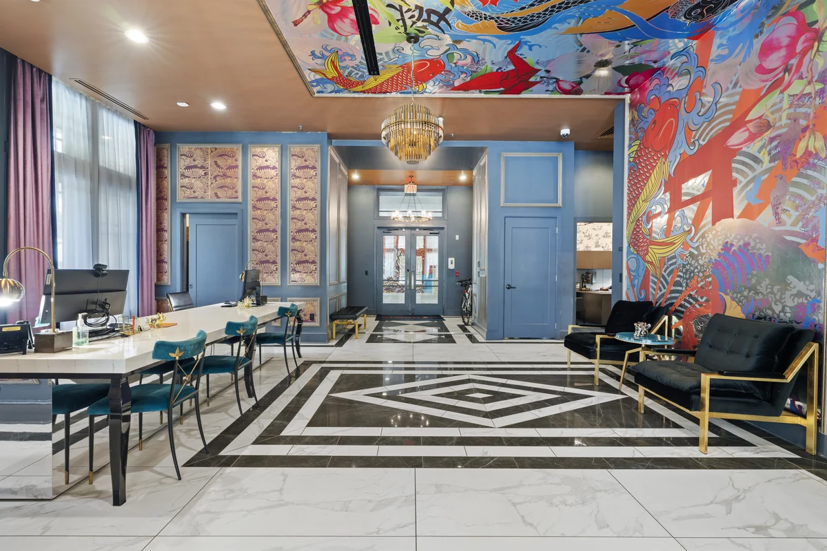 Apartment leasing lounge with blue walls, colorful artwork, and a seating area.