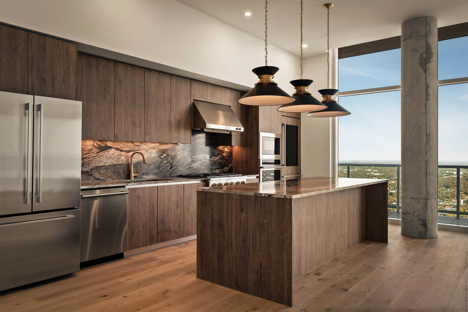Contemporary kitchen with walnut cabinetry, a stone island, and sculptural pendant lights beside floor-to-ceiling windows