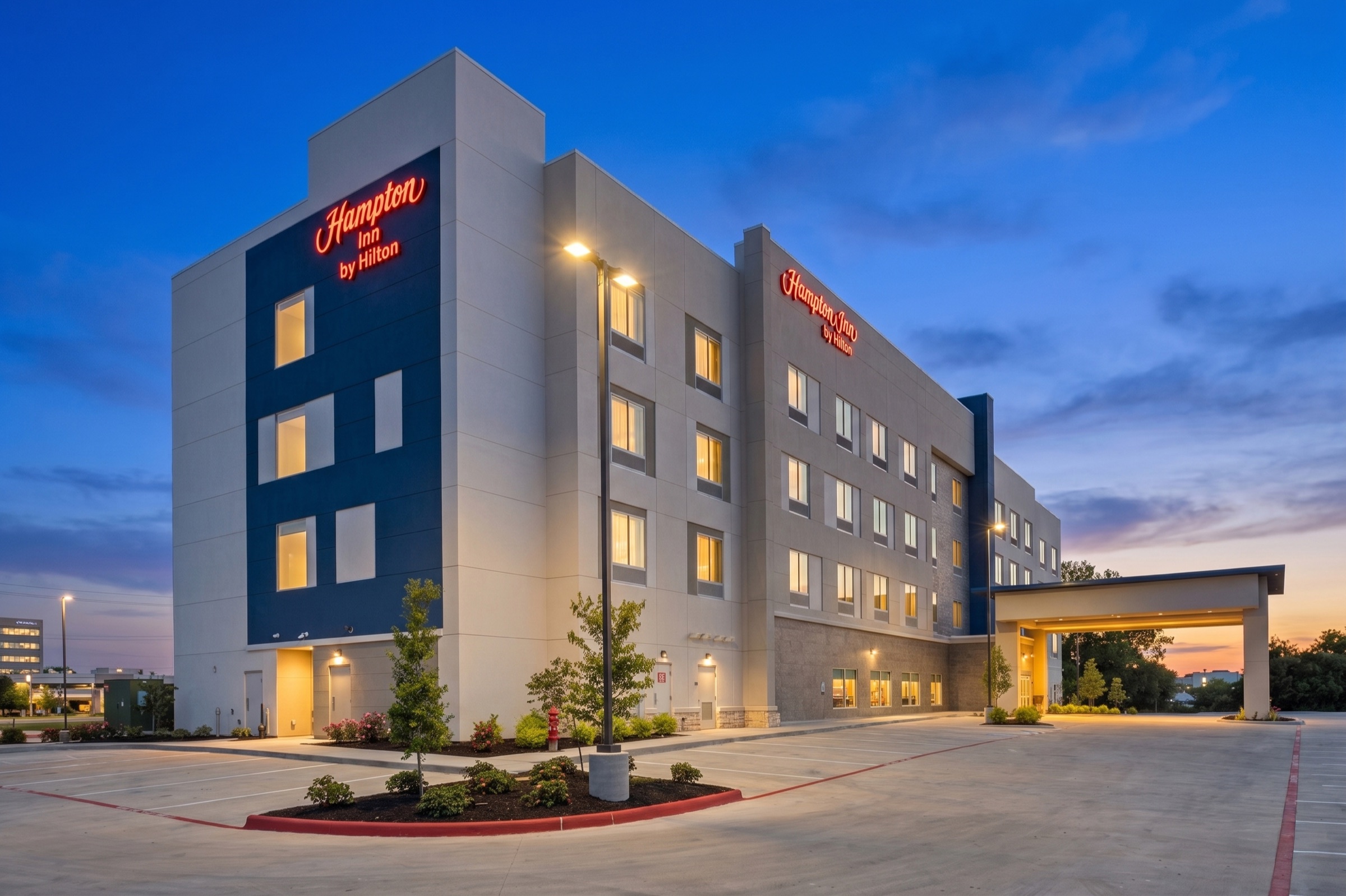 Hampton Inn hotel glowing at blue hour from an angled exterior view