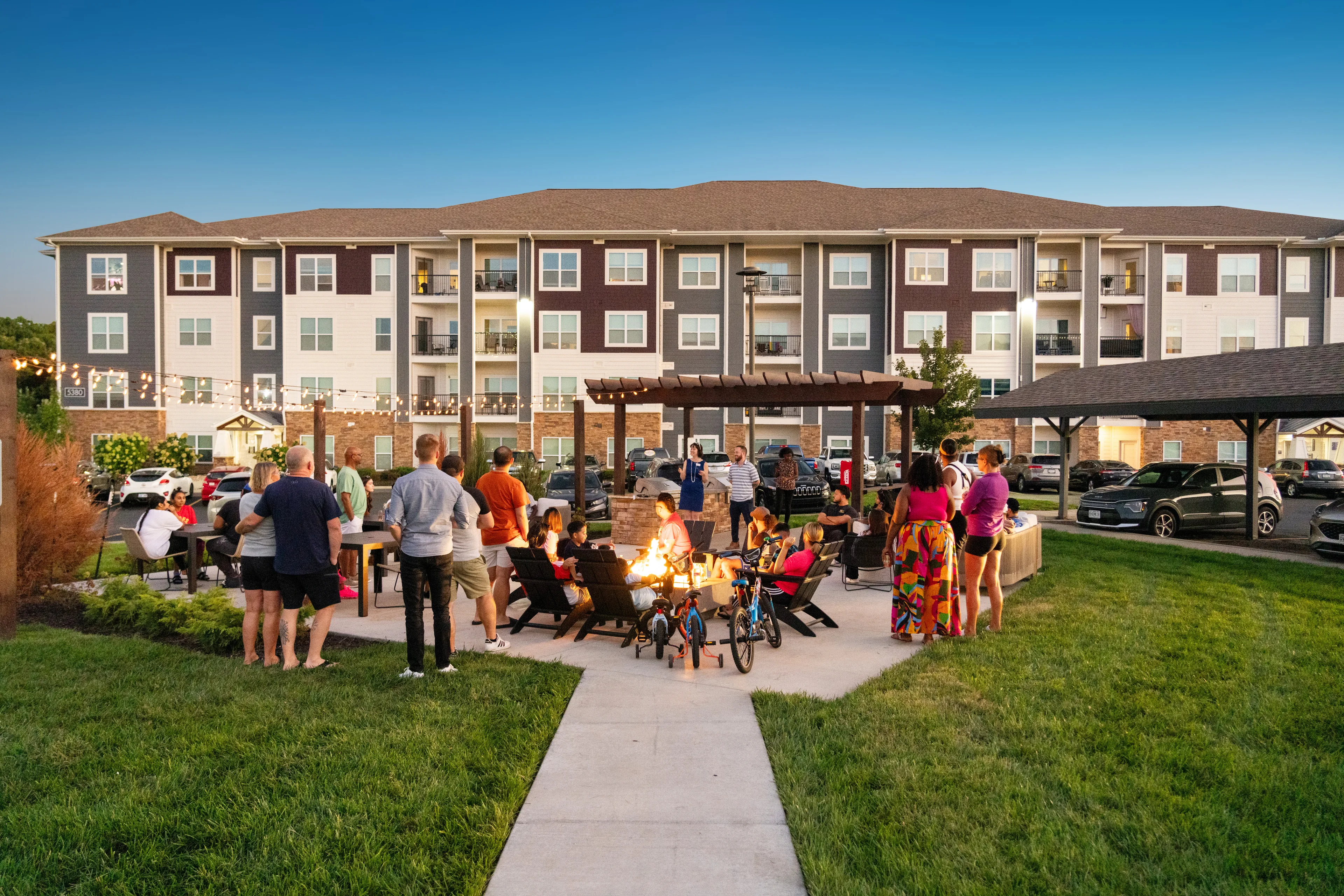 Neighbors gathering at an apartment community courtyard at dusk