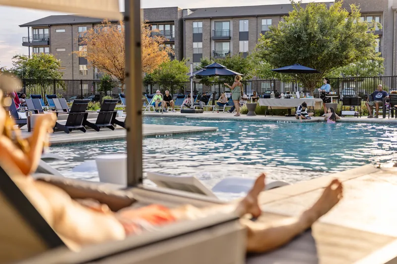 People gather and swim around an apartment community pool