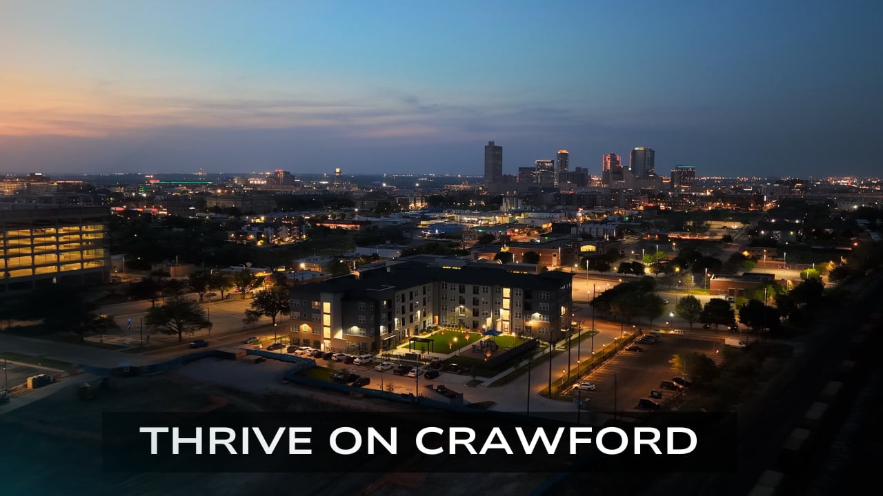 Twilight aerial of Thrive on Crawford and the city skyline in the property film poster