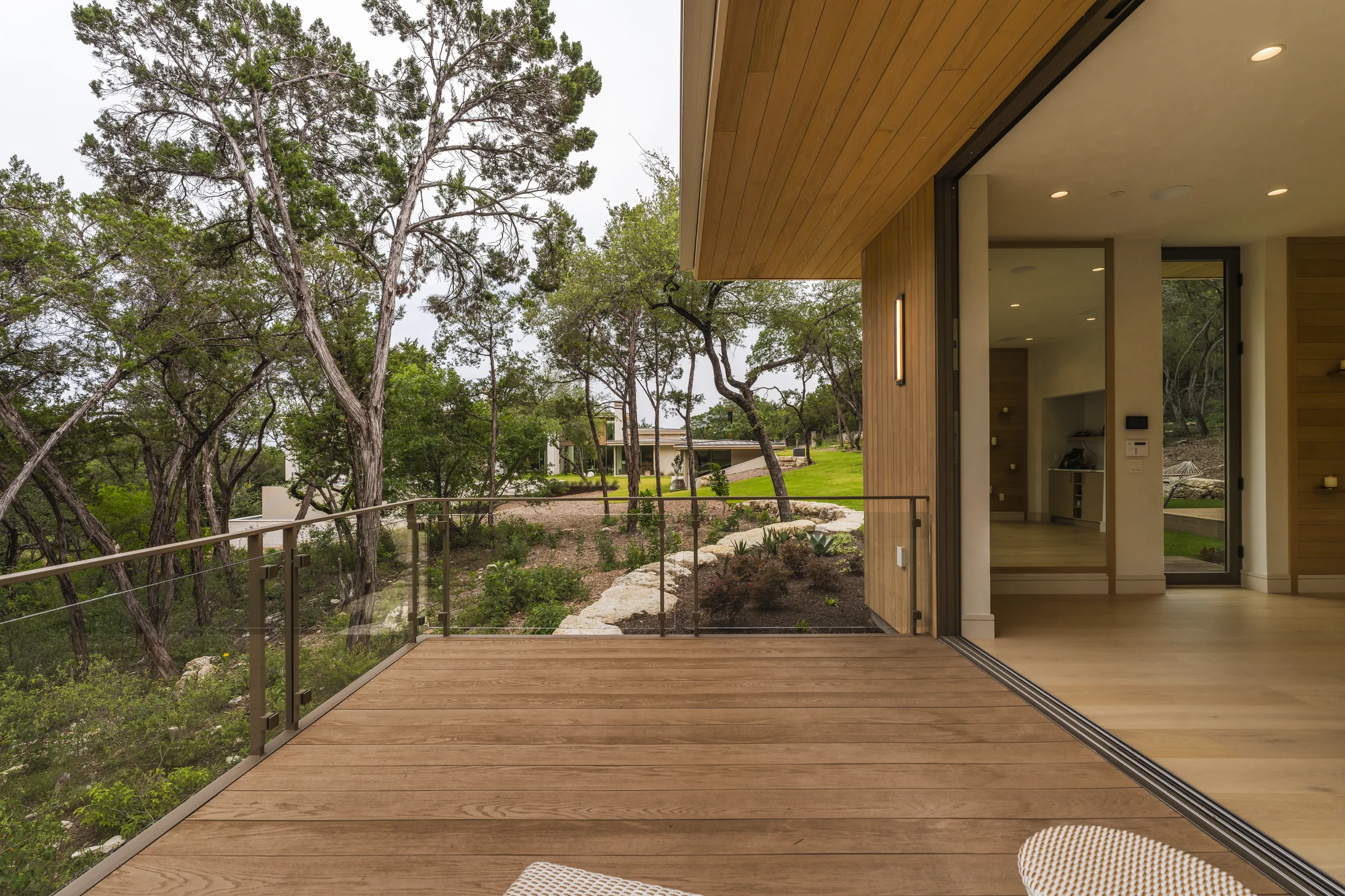Timber deck and glass facade opening toward the wooded landscape at Bennedict Lane