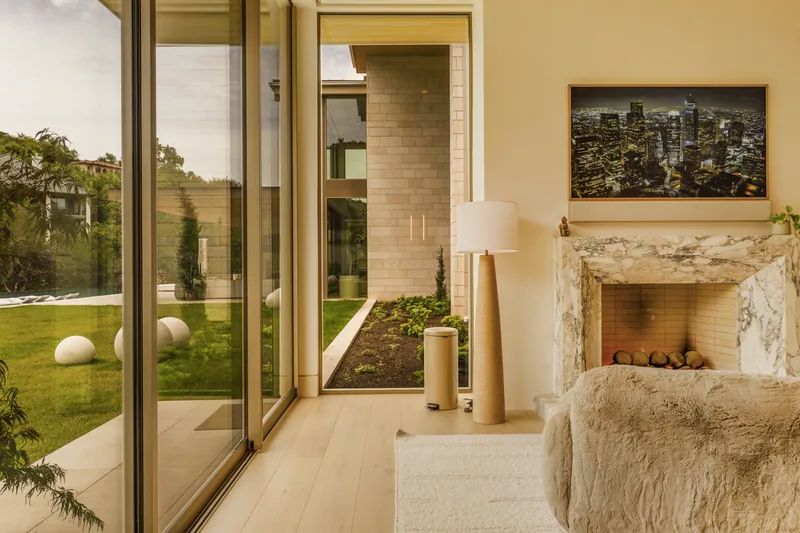 Stone fireplace and glass walls framing the landscaped courtyard