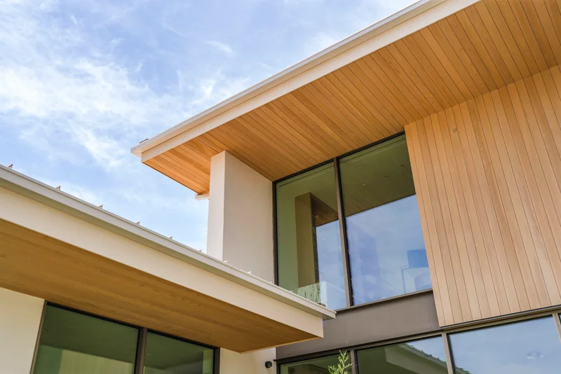 Intersecting timber rooflines and pale stone walls framing upper-story windows