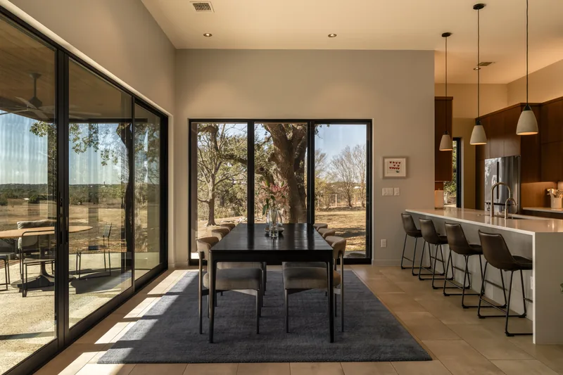 Glazed dining space connecting the kitchen to a Hill Country landscape