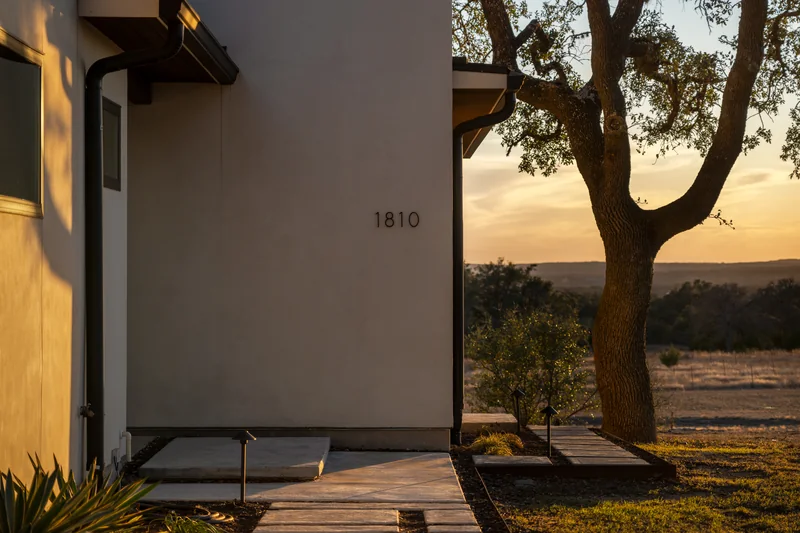 Warm sunset light grazing a modern home beside a mature oak tree