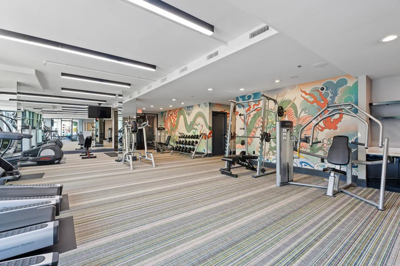 Apartment community fitness center with treadmills, weights and a colorful mural