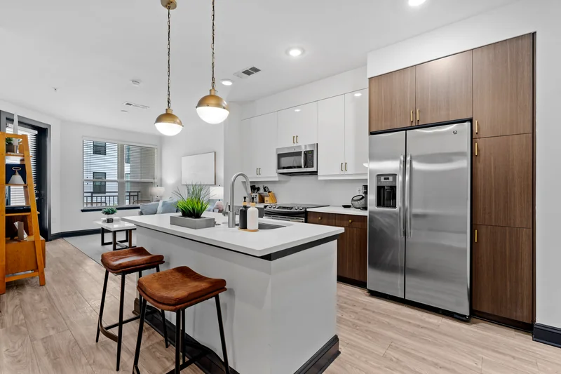 Apartment model kitchen with a generous island, timber cabinets and pendant lights