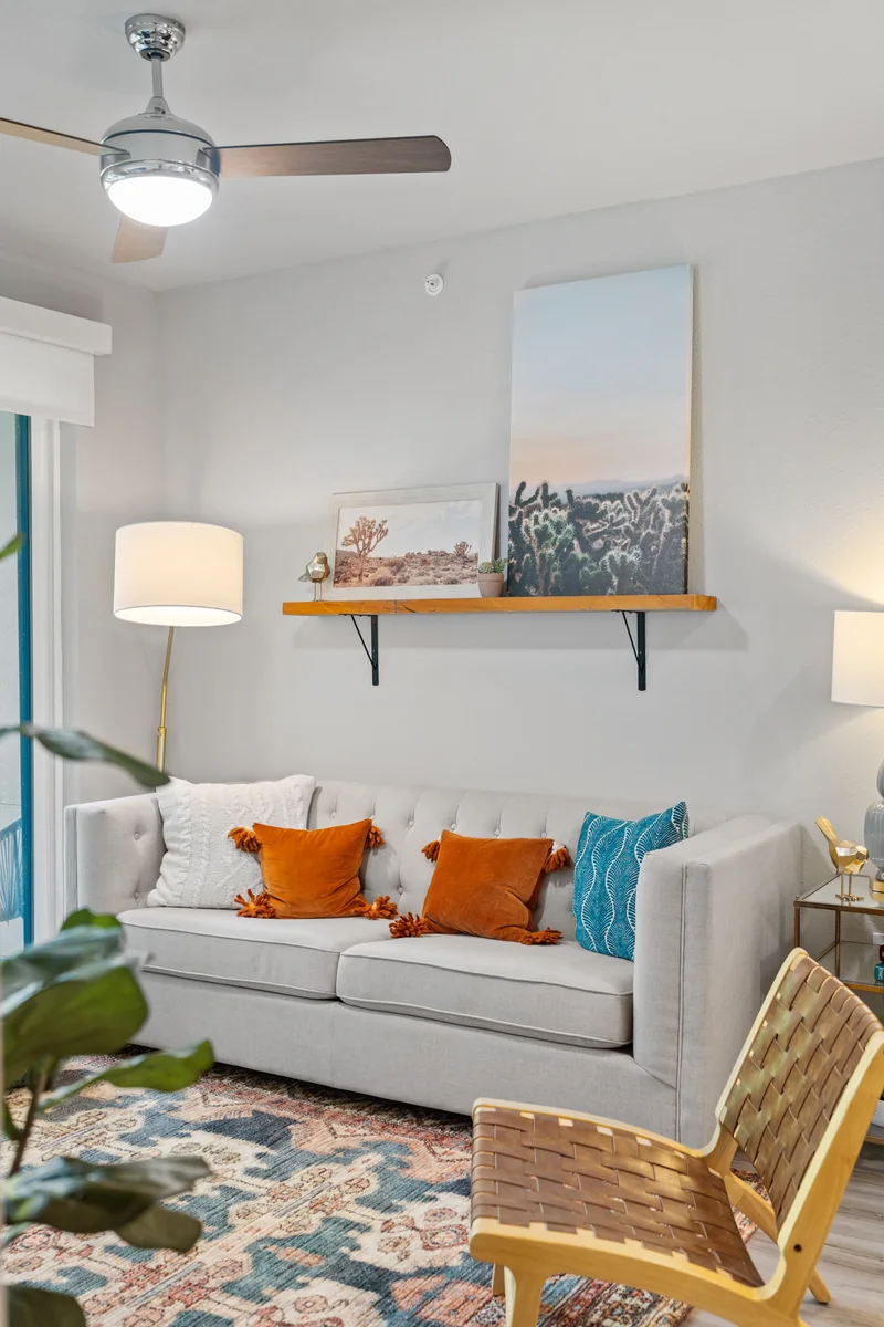 Furnished apartment living room with a white sofa, colorful cushions and a patterned rug