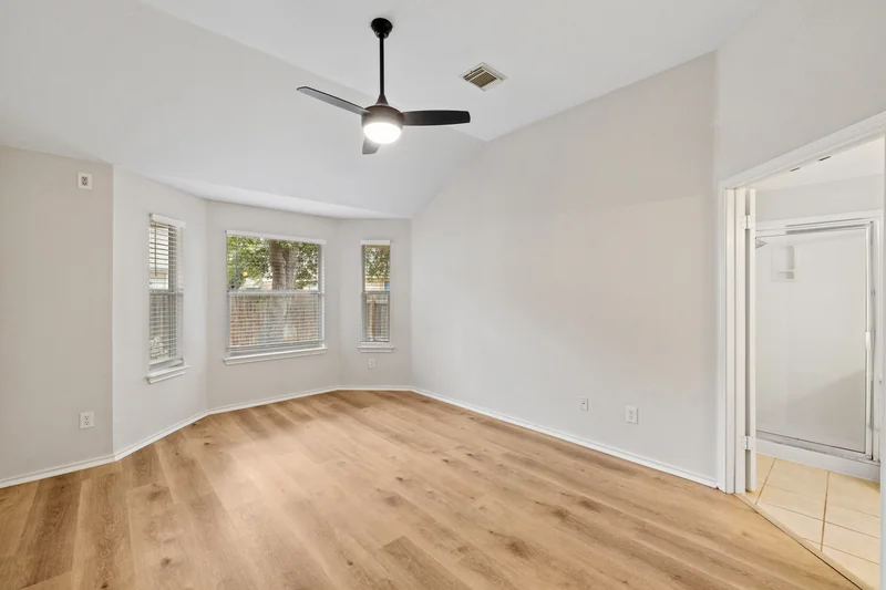 Unfurnished bedroom with bay windows and wood flooring