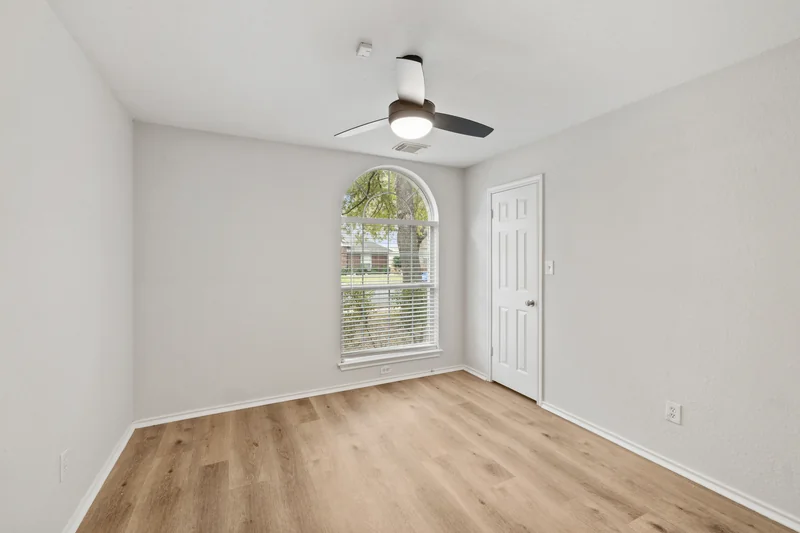 Unfurnished study with an arched window and wood flooring