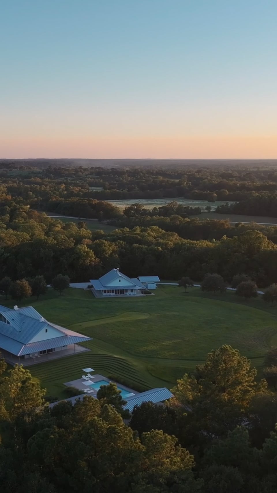 Aerial portrait of a ranch home and the surrounding land at sunset