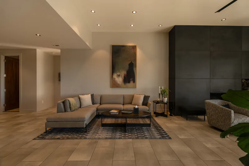 Modern living room with neutral furniture, stone fireplace and architectural lighting