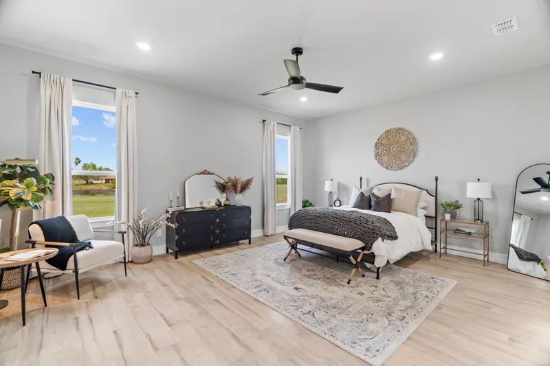 Comfortable residential bedroom with two windows and an open path around the bed