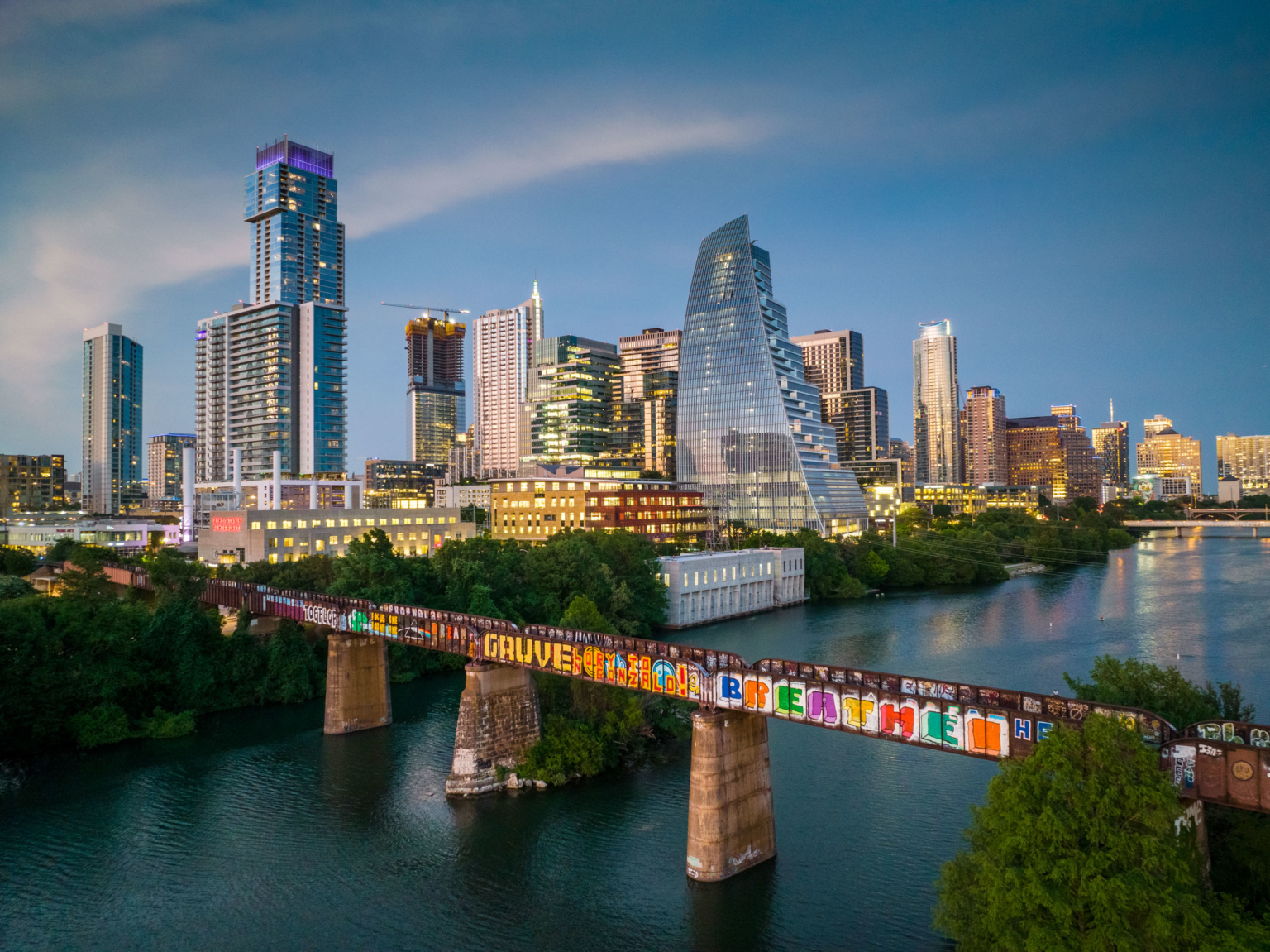 Austin skyline and the railroad bridge over Lady Bird Lake at dusk.