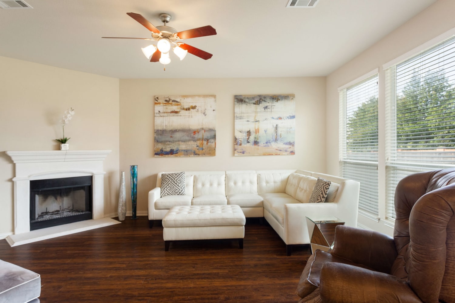 A bright living room with a white sectional, fireplace and wide windows