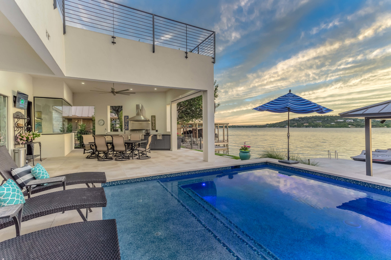 Lakefront home terrace and swimming pool at dusk.