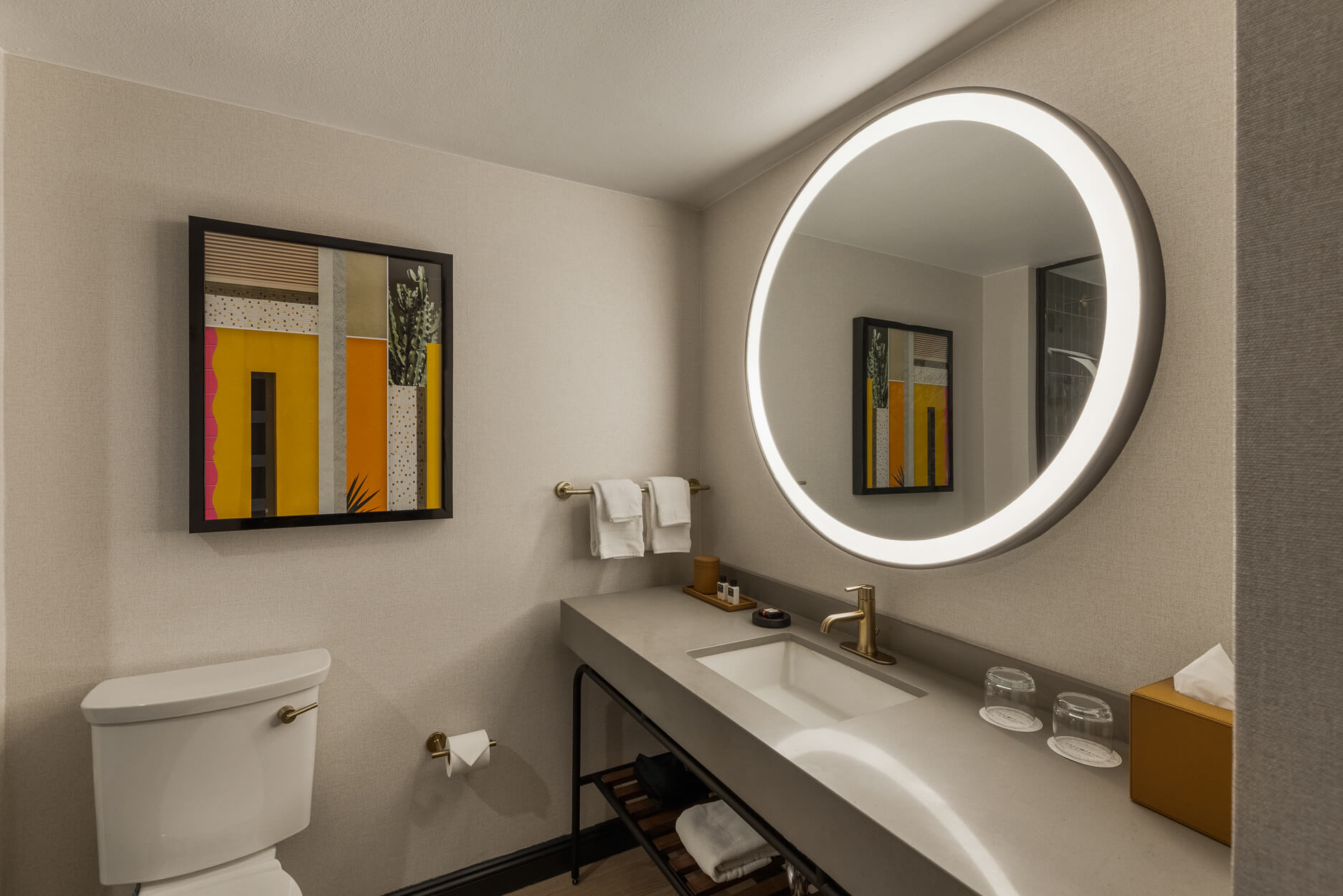 Hotel bathroom vanity with a circular illuminated mirror
