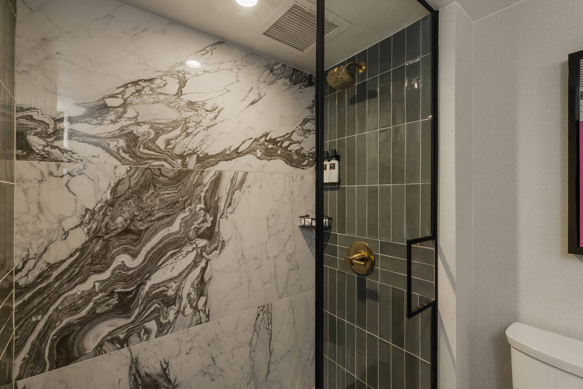 Hotel shower with patterned stone and dark tile