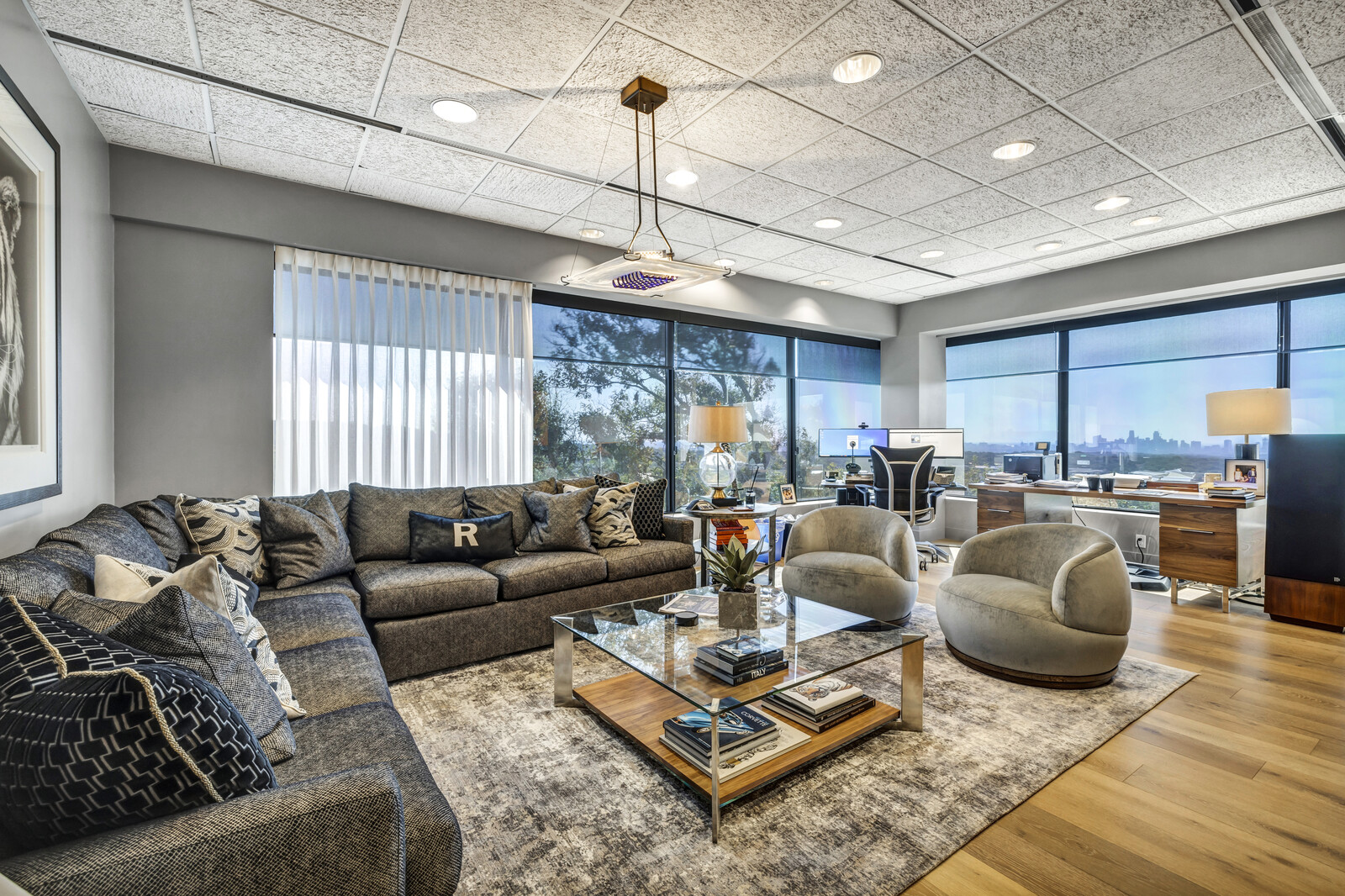 Furnished commercial office interior with seating, windows, and a skyline view.